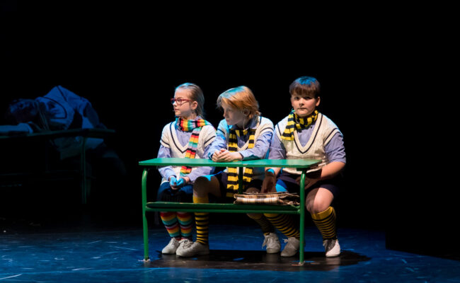 Zdjęcie ilustrujące uczniów Bąka, Osę i Galaretę siedzących w ławce szkolnej.
