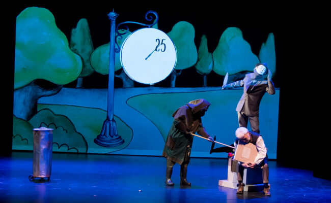 Zdjęcie ilustruje scenę gdzie Zamiatacz Ulic przegania miotłą Starszego Pana Kurzugórę miotłą. Kurzugóra siedzi pod pomnikiem Poety.